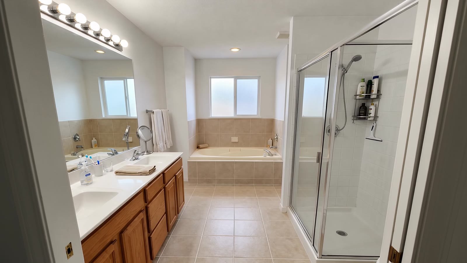 The same bathroom before: cream tiles, glass shower cubicle and a built-in bath